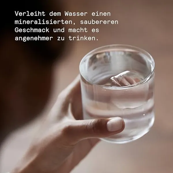 Hand houdt glas helder gefilterd water vast, gemineraliseerd met magnesium