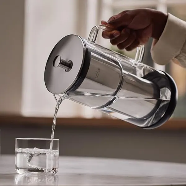 Aarke Purifier schenkt gefilterd water in een glas via de glazen handgreep