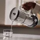 Aarke Purifier schenkt gefilterd water in een glas via de glazen handgreep