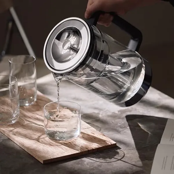 Aarke Purifier Large schenkt gefilterd water in een glas op marmeren onderlegger