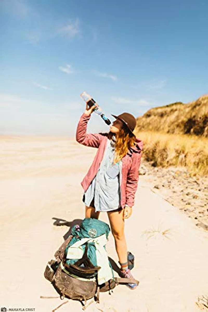 Hiker drinkt gefilterd water met Sawyer Squeeze filter op het strand