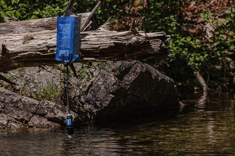 Sawyer Squeeze opgehangen als gravitysysteem aan een boomstam boven een beek